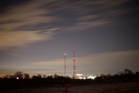 Communications towers and emitting smokestacks against the morning sky.